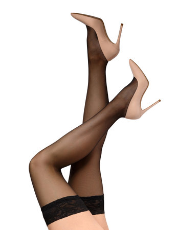 Slender female legs in black stockings with a beautiful openwork elastic band and elegant beige high-heeled shoes on a white background, isolated. Close-up of the graceful legs of a girl in stockingsの写真素材