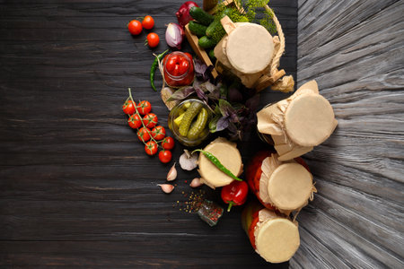 Canned cherry tomatoes and cucumbers in jars, fresh vegetables, spices and herbs for marinade on a wooden background, top view. Pickled vegetables.の写真素材