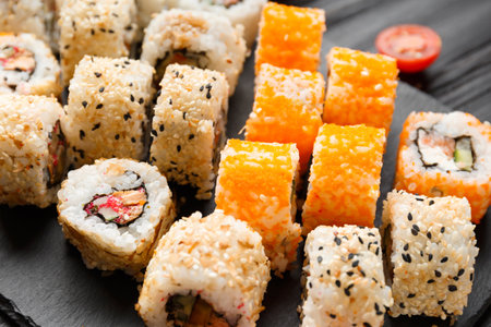 Set of sushi rolls with salmon, tuna, caviar, sesame seeds on a black stone slate plate, close-up.の写真素材