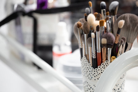 A set of professional brushes and applicators for makeup of various sizes and shapes in an organizer on the makeup artist's desktop. Beauty tools. Brushes in a glass.の写真素材
