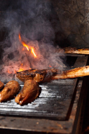 Appetizing juicy tomahawk steaks, ribeye and sirloin laid out on a barbecue grill over a burning...