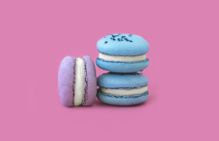 Blue and purple macarons on a bright pink background. A French dessert. Multicolored macarons.e multicolored macarons on a pink backgroundの写真素材