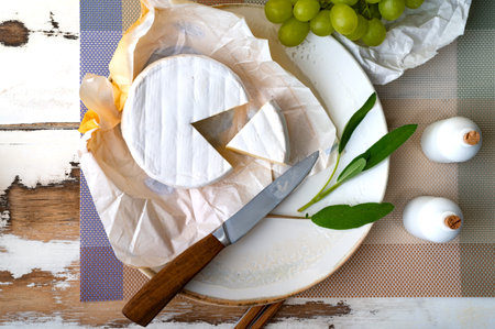 Camembert cheese with grapes and olives on rustic wooden backgroundの写真素材