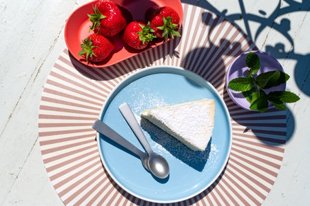 Strawberry cheesecake on a blue plate on a white backgroundの写真素材