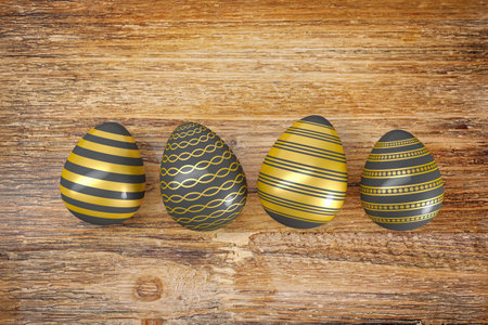 3d render of four gold, black, painted easter eggs on rustic dark wood tableの写真素材