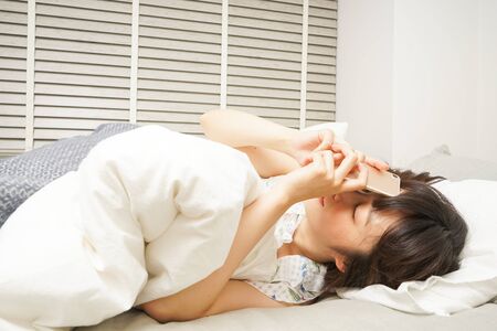 Young woman using a cellphone before sleepingの写真素材