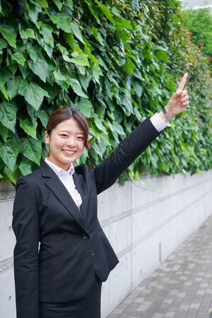Businesswoman pointing to upside outdoorsの写真素材