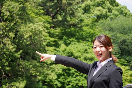 Businesswoman pointing to upside outdoorsの写真素材