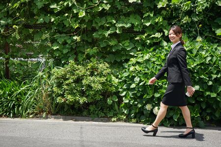 Businesswoman walking outdoors with smileの写真素材
