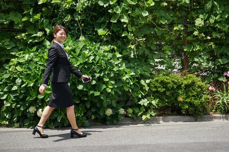 Businesswoman walking outdoors with smileの写真素材