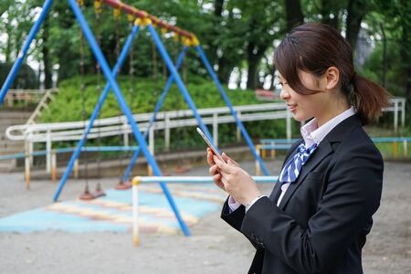 Student in uniform using a smartphone with smileの写真素材