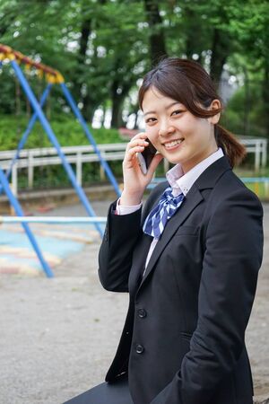 Student in uniform using a smartphone with smileの写真素材