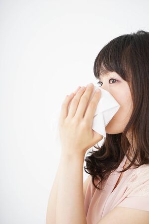 Young woman blowing her noseの写真素材