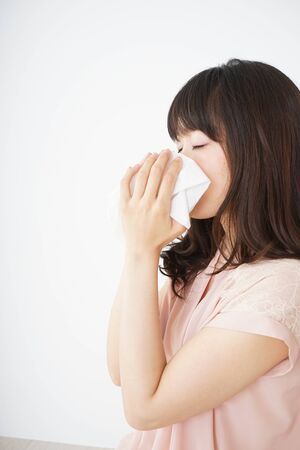 Young woman blowing her noseの写真素材