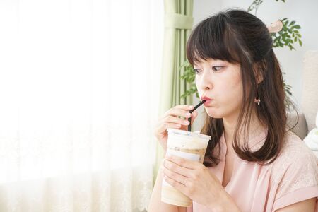 Young woman drinking coffee at roomの写真素材