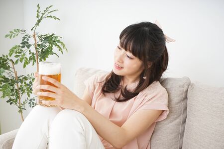Young woman drinking beer at homeの写真素材