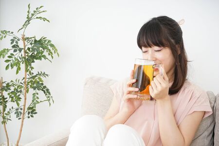Young woman drinking beer at homeの写真素材