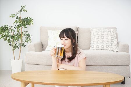 Young woman drinking beer at homeの写真素材