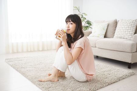 Young woman drinking beer at homeの写真素材