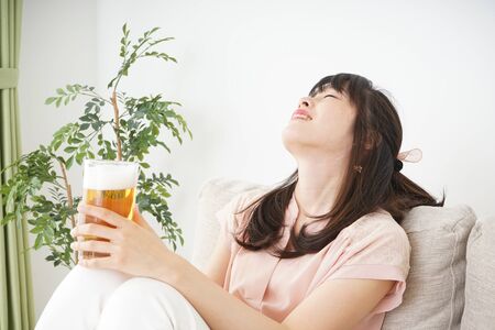 Young woman drinking beer at homeの写真素材