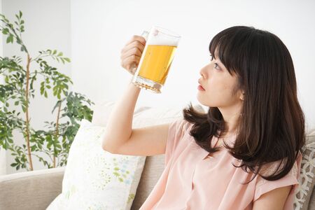 Young woman drinking beer at homeの写真素材