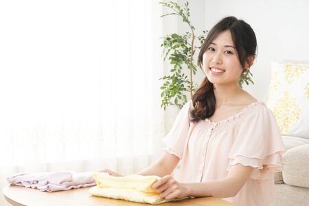 Young woman folding her clothesの写真素材