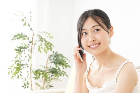 Young woman using a smart phone in her roomの写真素材