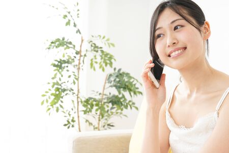 Young woman using a smart phone in her roomの写真素材