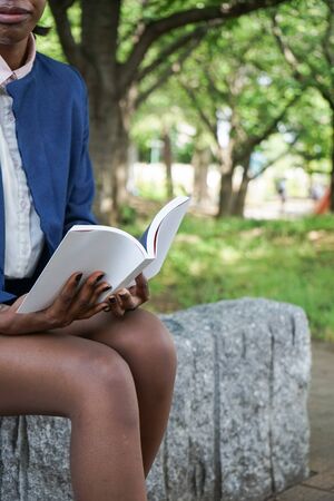 african woman reading a book at parkの写真素材