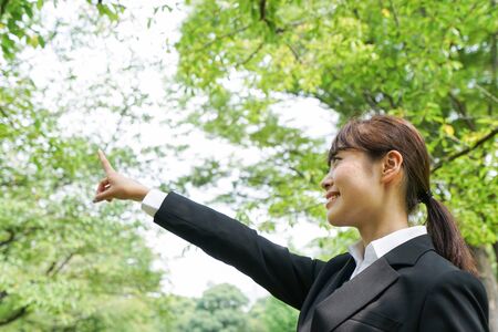 Business woman pointing with green backgroundの写真素材
