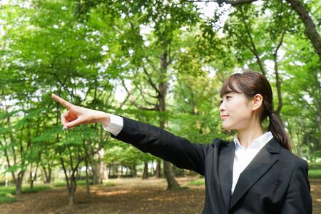 Business woman pointing with green backgroundの写真素材
