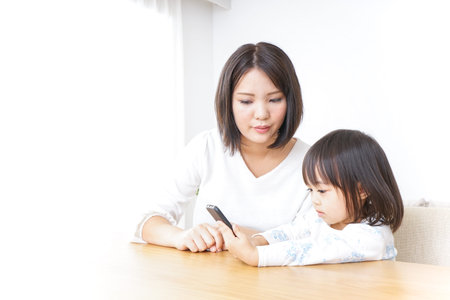 Child using smartphone with motherの写真素材