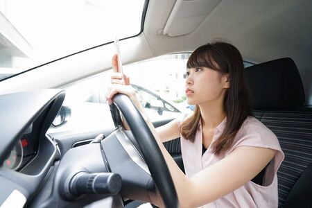 Driving woman using smartphoneの写真素材
