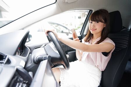 Driving woman using smartphoneの写真素材