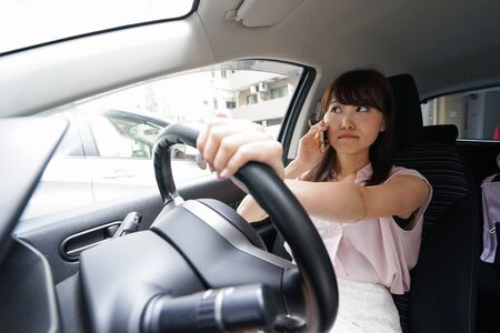 Driving woman using smartphoneの写真素材