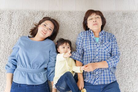 Child, mother, and grandmother lying in roomの写真素材