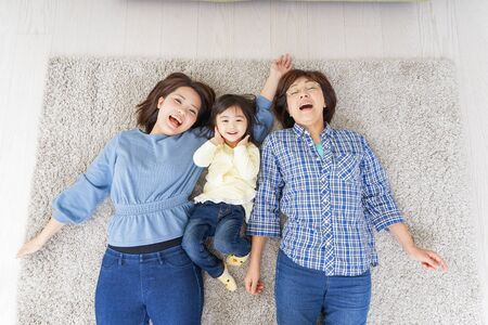 Child, mother, and grandmother lying in roomの写真素材