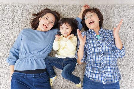 Child, mother, and grandmother lying in roomの写真素材