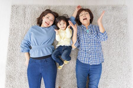 Child, mother, and grandmother lying in roomの写真素材