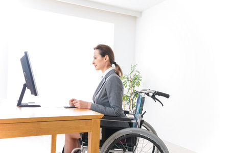 Disabled business woman in wheelchair working at her desk in the office