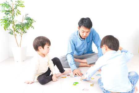 Child playing board game with father and two kids in the living room