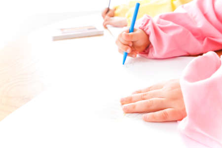 Little girl drawing with colored pencils on white paper at home.の写真素材