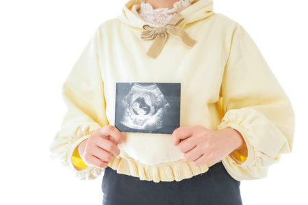 Young pregnant woman holding ultrasound scan on white background, closeup. Space for text