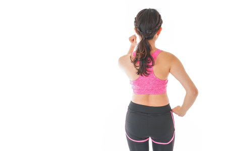 Young woman wearing sportswear, back view, isolated on white background