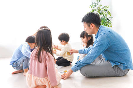 Happy asian family playing board game at home. Father, mother and children having fun together.の写真素材