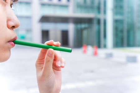 Close-up of a woman using a green pen in the streetの写真素材