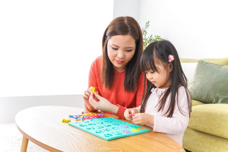 Mother and daughter playing with educational toys together at home. Happy family concept.