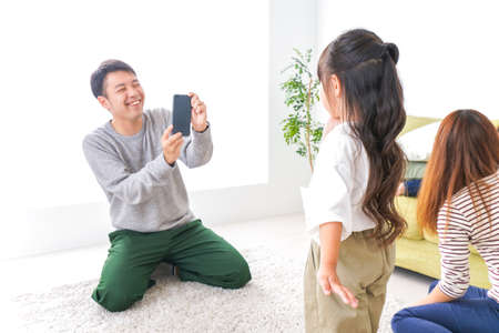 Young asian family sitting on the floor at home and taking selfieの写真素材