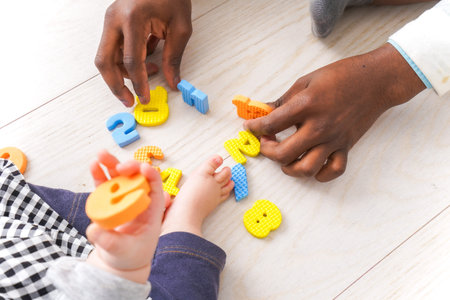 Top view of African American father and son playing with colorful wooden letters