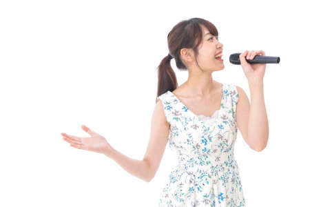 Young woman singing karaoke and holding a microphone high quality photoの写真素材